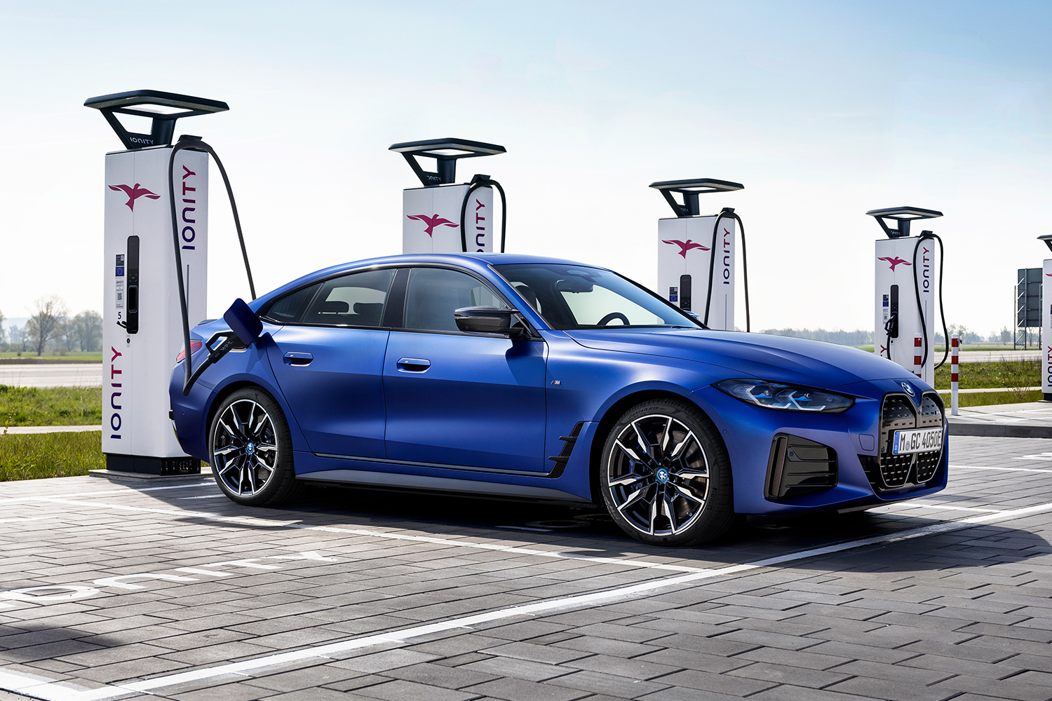 A blue 2022 BMW i4 M50 electric sedan charging at bank of Ionity EV charge stations