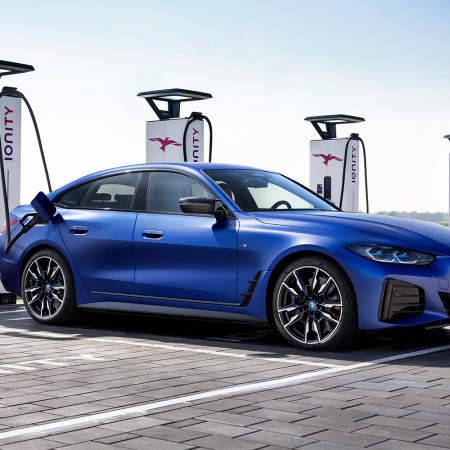 A blue 2022 BMW i4 M50 electric sedan charging at bank of Ionity EV charge stations