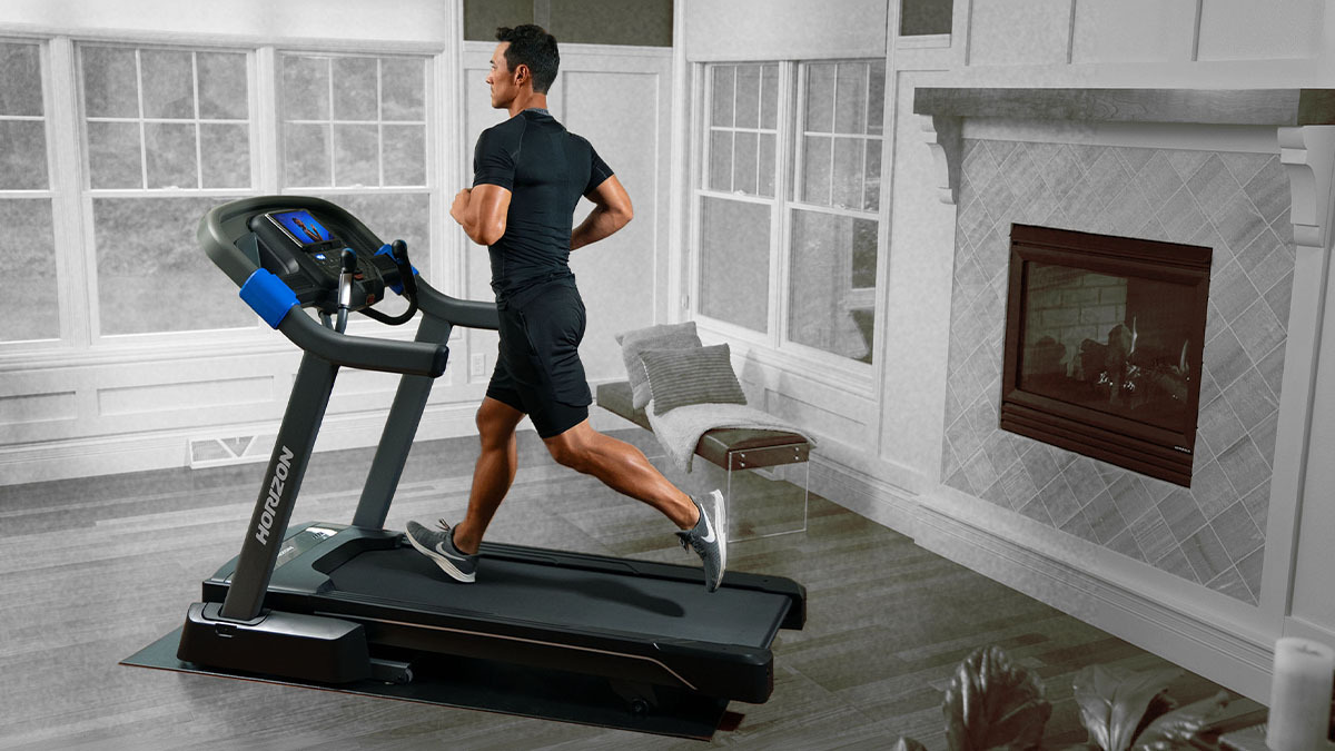 A man running on the Horizon Fitness 7.0 AT Studio Series Treadmill in a house