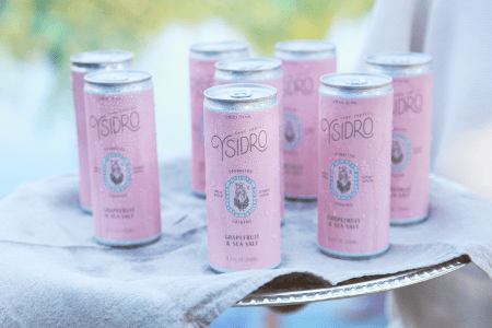 A server holding up a platter of Ysidro's sake spritz, a canned cocktail from Montecito