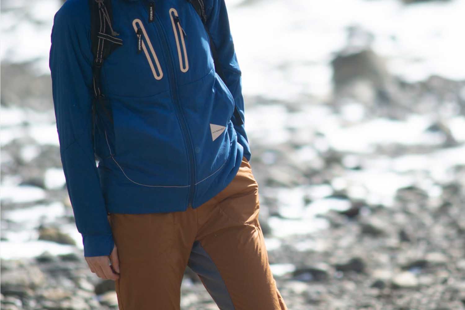 a model in a blue And Wander jacket outdoors