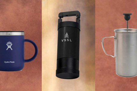 A VSSL JAVA Manual Hand Coffee Grinder, Snow Peak Titanium French Press and a Hydro Flask Mug on brown textured backgrounds.