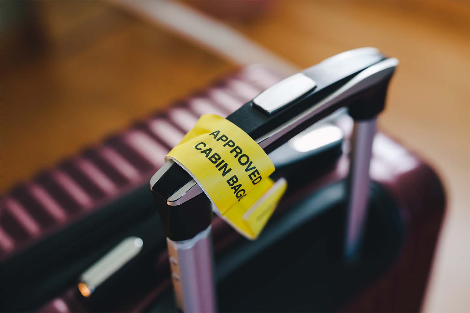 Approved cabin bag label attached to a handle of a carry-on suitcase