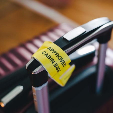 Approved cabin bag label attached to a handle of a carry-on suitcase