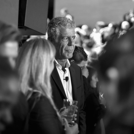 Anthony Bourdain standing in a crowd at a screening looking pensive.