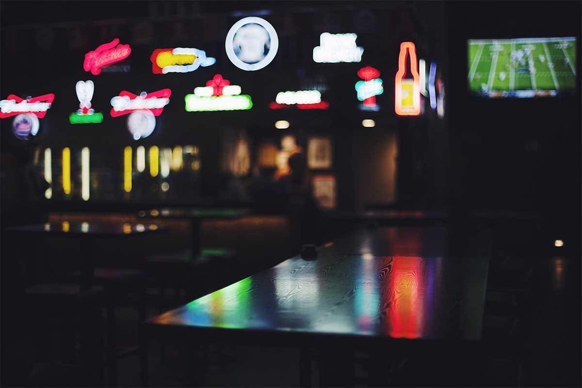 An empty bar with several beer signs (blurred). The booze industry has had some less-than-stellar numbers recently.