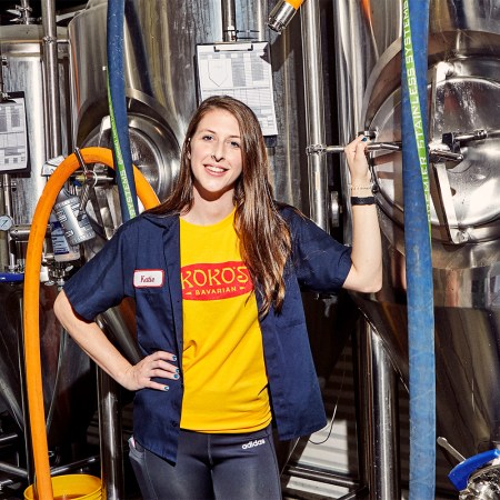 Head brewer Katie Lowe of Koko's Bavarian standing next to their craft beer brewing equipment