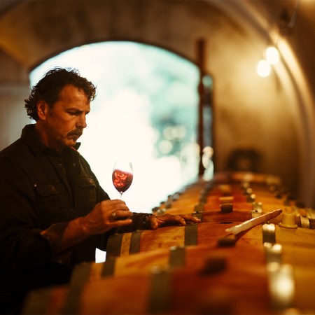 Napa Valley winemaker Chris Carpenter stands by barrels swirling a glass of red wine