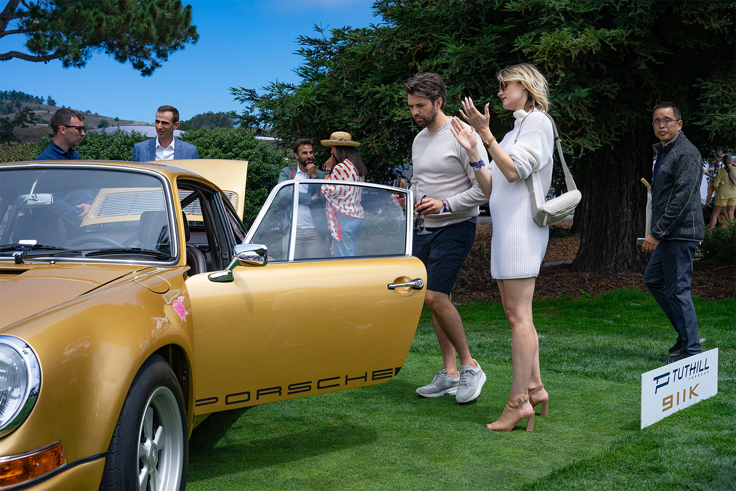 Spectators beside a gold Porsche at the Rolex Monterey Motorsports Reunion