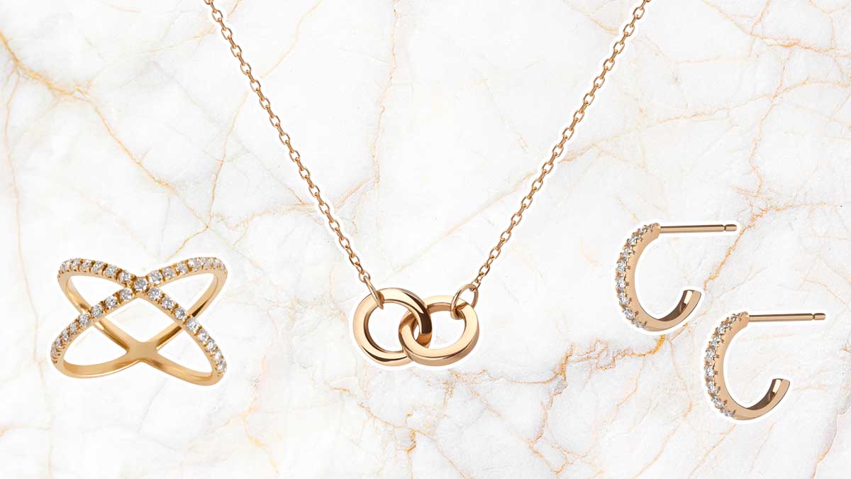 Gold ring, necklace and earrings from Aurate, on a gold and marble background