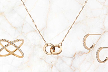 Gold ring, necklace and earrings from Aurate, on a gold and marble background