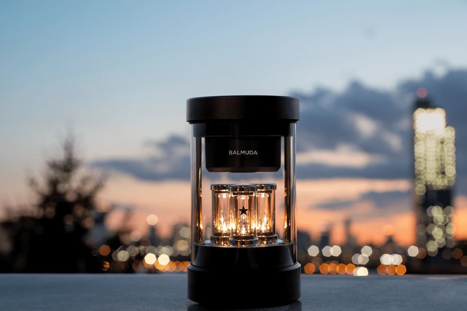 a BALMUDA speaker on a table with a city-scape background