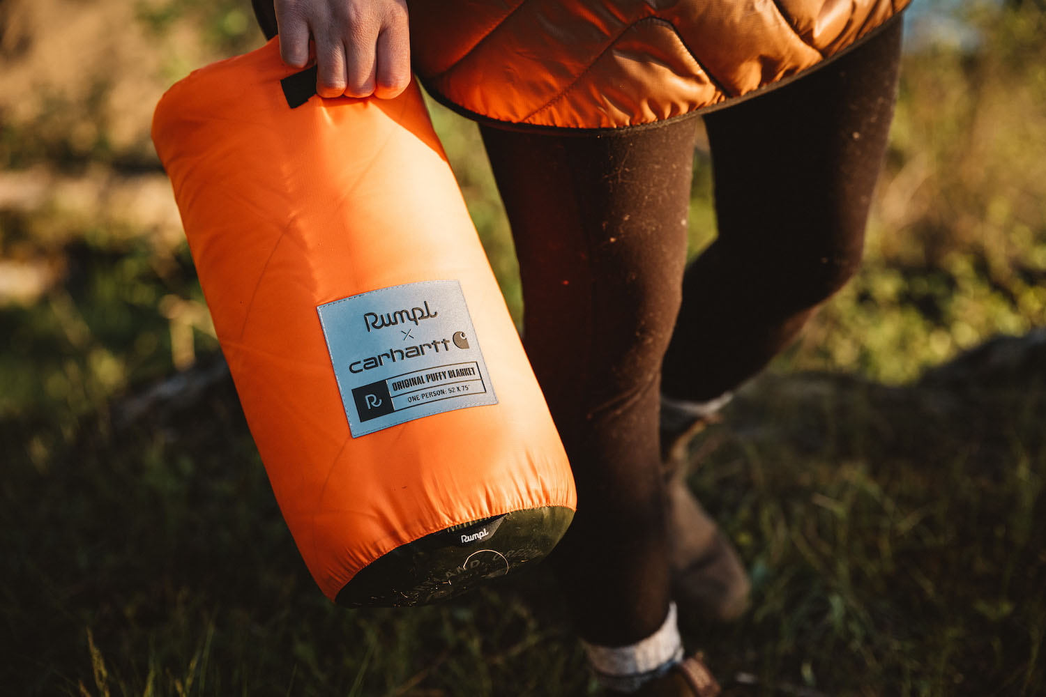 a model carrying a safety cone orange RUMPL x Carhartt blanket outside