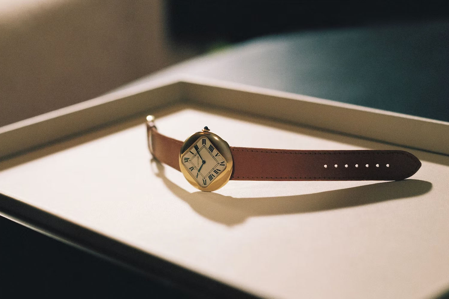 a Cartier Pebble watch on a golden tray