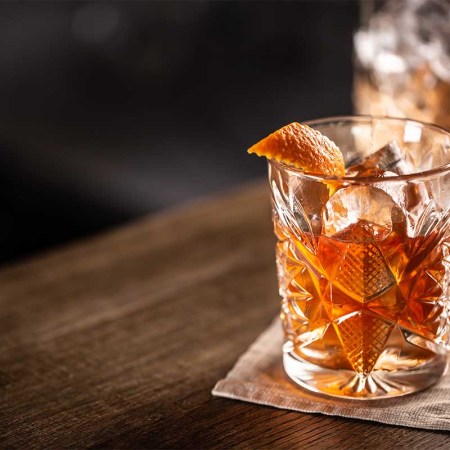 Old fashioned whiskey drink on ice with orange zest garnish. There are numerous ways to improve and perfect an Old Fashioned.