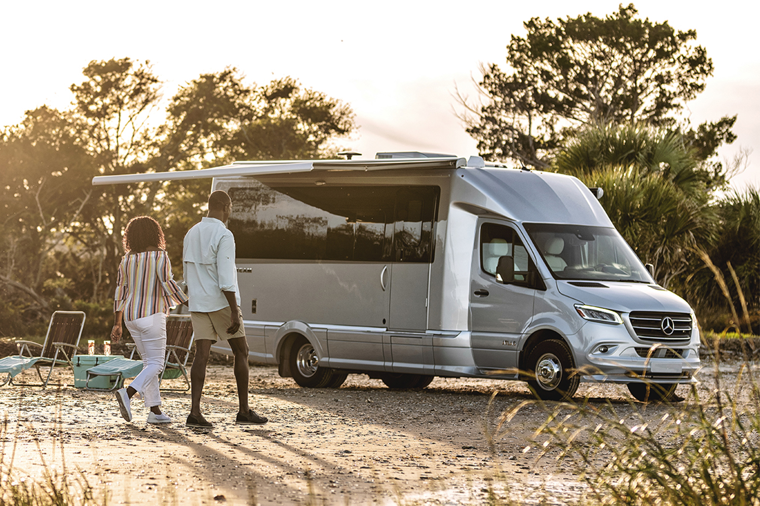 A couple walking on the beach towards their Airstream Atlas Class B motorhome