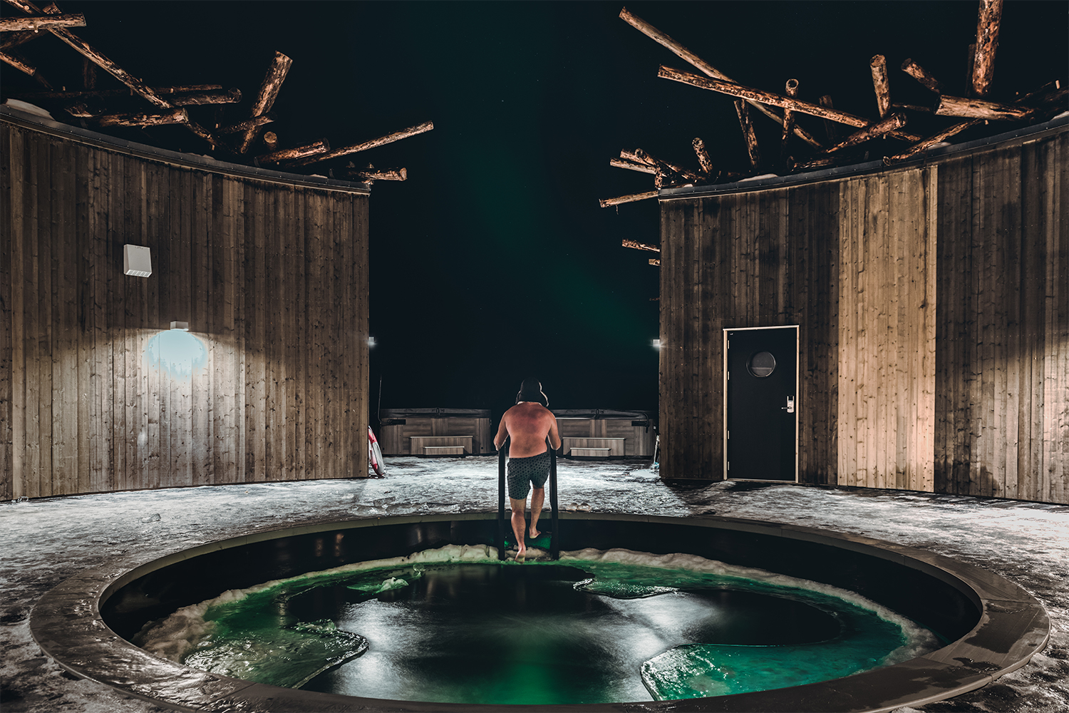 A man climbing out of the almost frozen river in the middle of the pool at Arctic Bath in Swedish Lapland