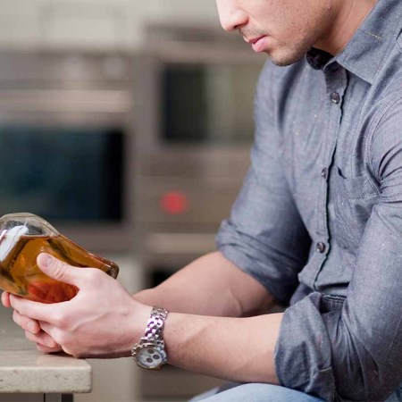 A man examining a whiskey bottle in a kitchen. Nutrition labels may be coming to alcohol bottles.