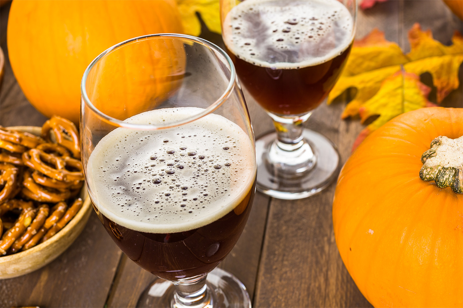 Craft pumpkin beer in beer glasses with salty pretzels and popcorn.