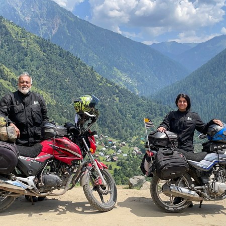 Qazi and Ghazal Farooqi posing in front of their motorcycles in the mountains of pakistan