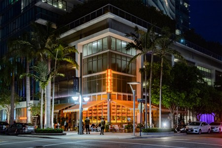 The facade of Italica, a new restaurant in Miami, Florida, with the neon sign lit up at night