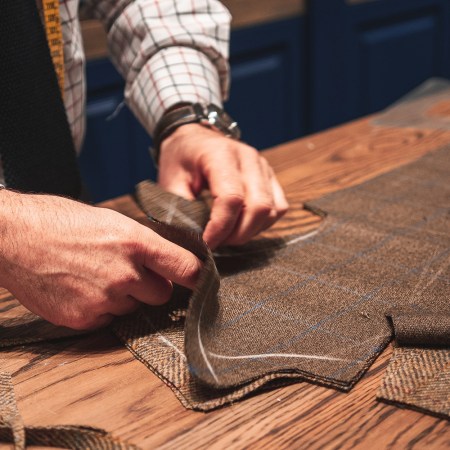 A tailor's hands close up stitching a piece of men's clothing