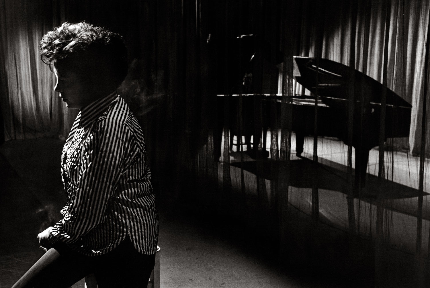 black and white photo of judy garland sitting in front of a piano