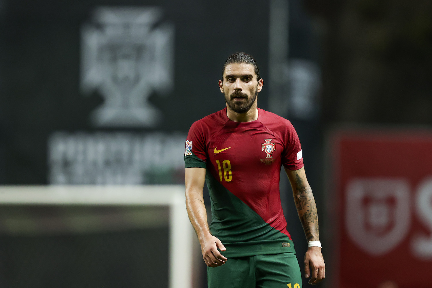 a player in a red and green split soccer jersey