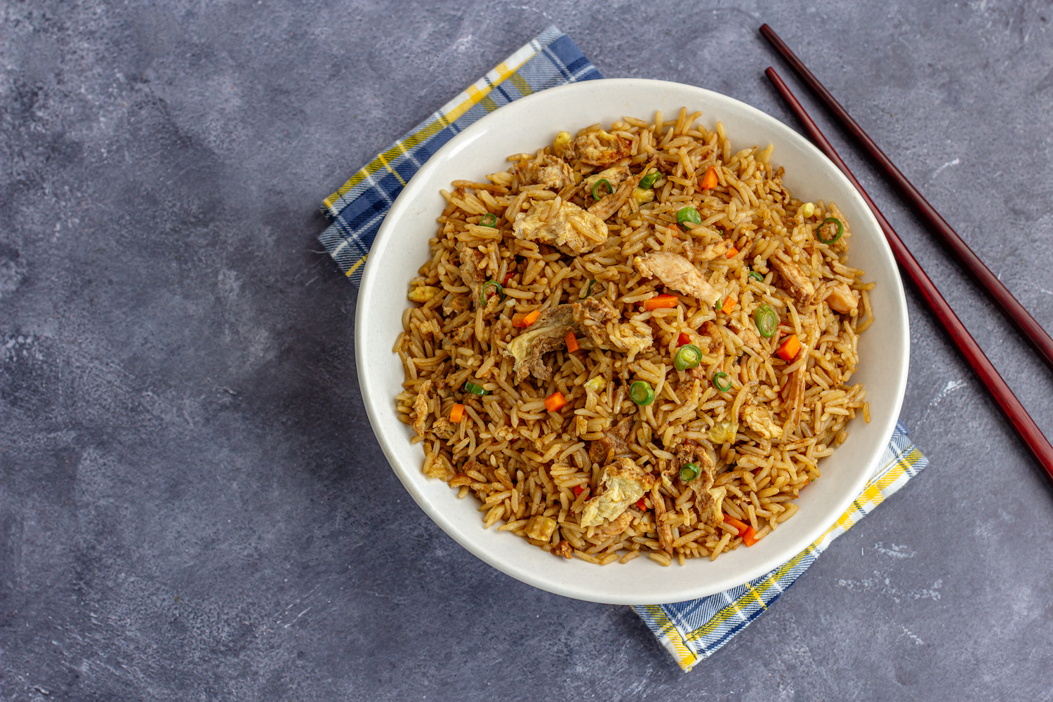 a bowl of leftover turkey fried rice sitting on top of a plaid napkin