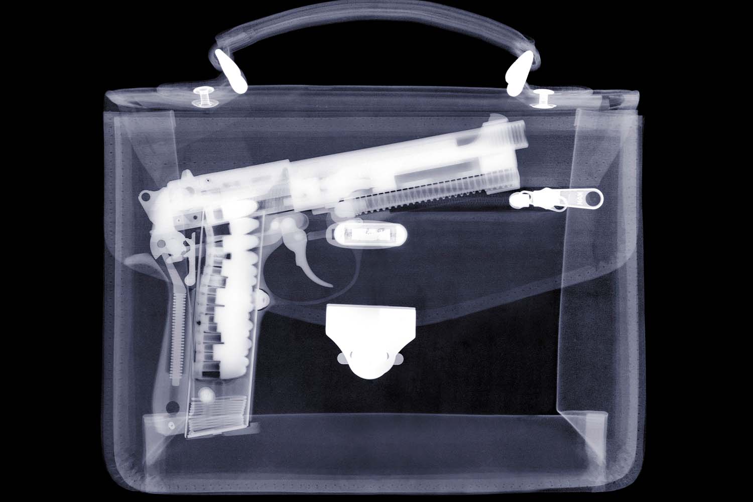 An x-ray of a handbag showing a gun inside. According to TSA, American travelers are still bringing guns to airports despite massive fines.