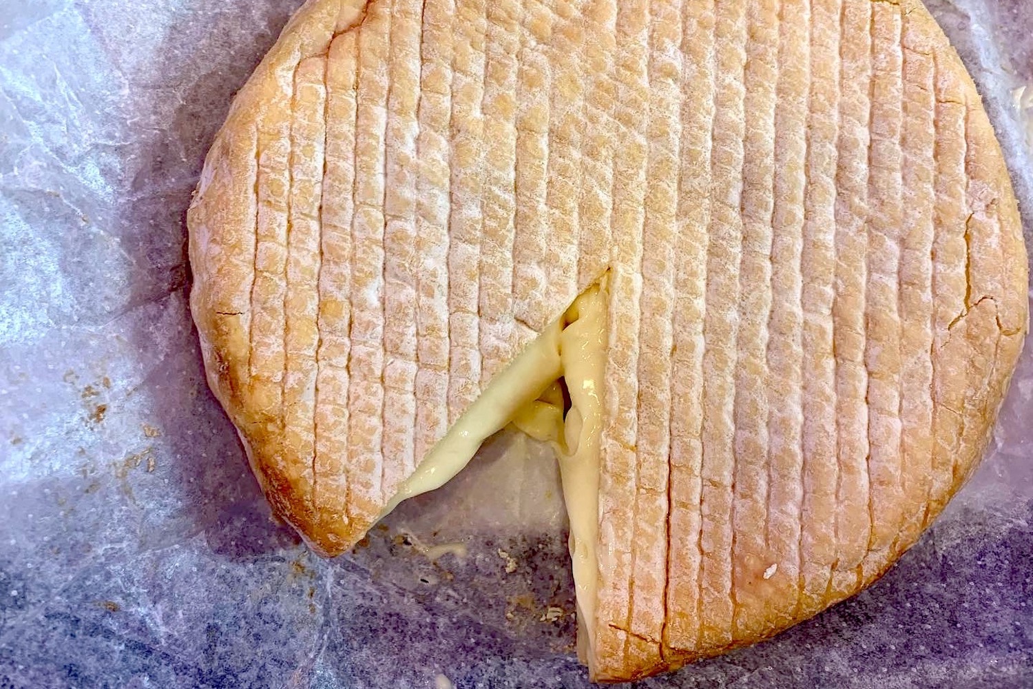 soft washed rind cheese wheel with one piece cut out