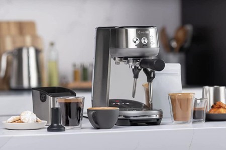 A Breville Express espresso machine on a counter with a few cups of coffee. Amazon is hosting a sale on these machines.