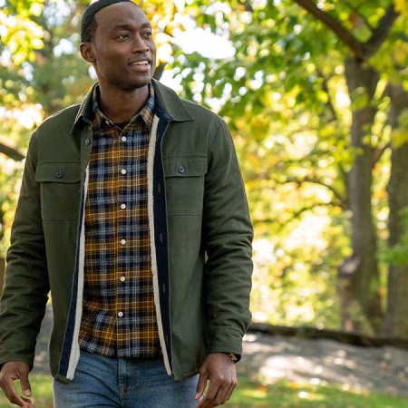 A man wearing various Jachs NY clothing (jacket, shirt, jeans) standing outside in a brightly-lit forest. JACHS NY is currently throwing a Black Friday sale.