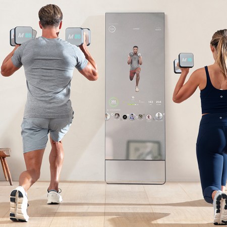 A man and woman working out with the Lululemon Studio Mirror, which is currently 50% off