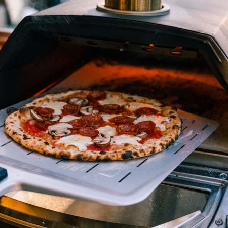 A pizza going into the Ooni Karu 16 Multi-Fuel Pizza Oven, now on sale for Black Friday