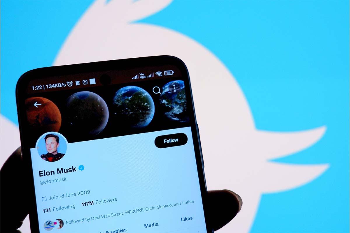 In this photo illustration, Twitter account of Elon Musk is displayed on a smartphone with a Twitter logo in the background. A former employee suggests Twitter may crash during the World Cup