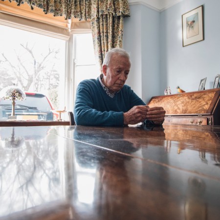 An old man sits alone at his living room table.