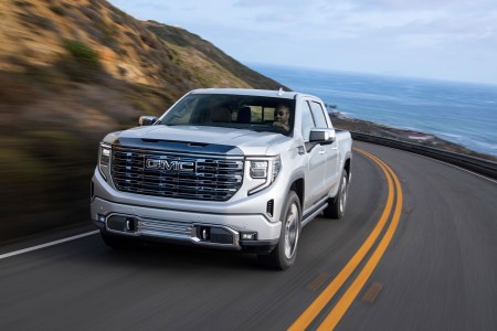 The 2022 GMC Sierra Denali Ultimate driving down a road next to the ocean. Here's our full review of the luxury pickup truck.