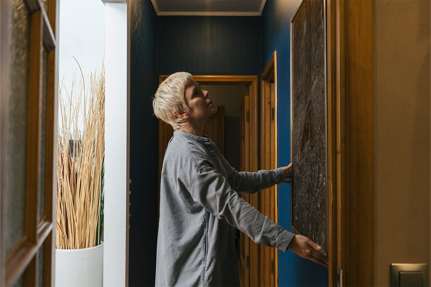 Woman hanging picture frame on wall at home