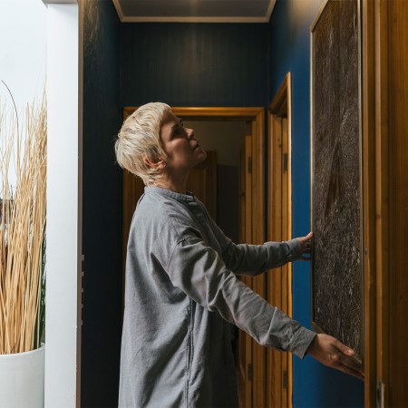 Woman hanging picture frame on wall at home