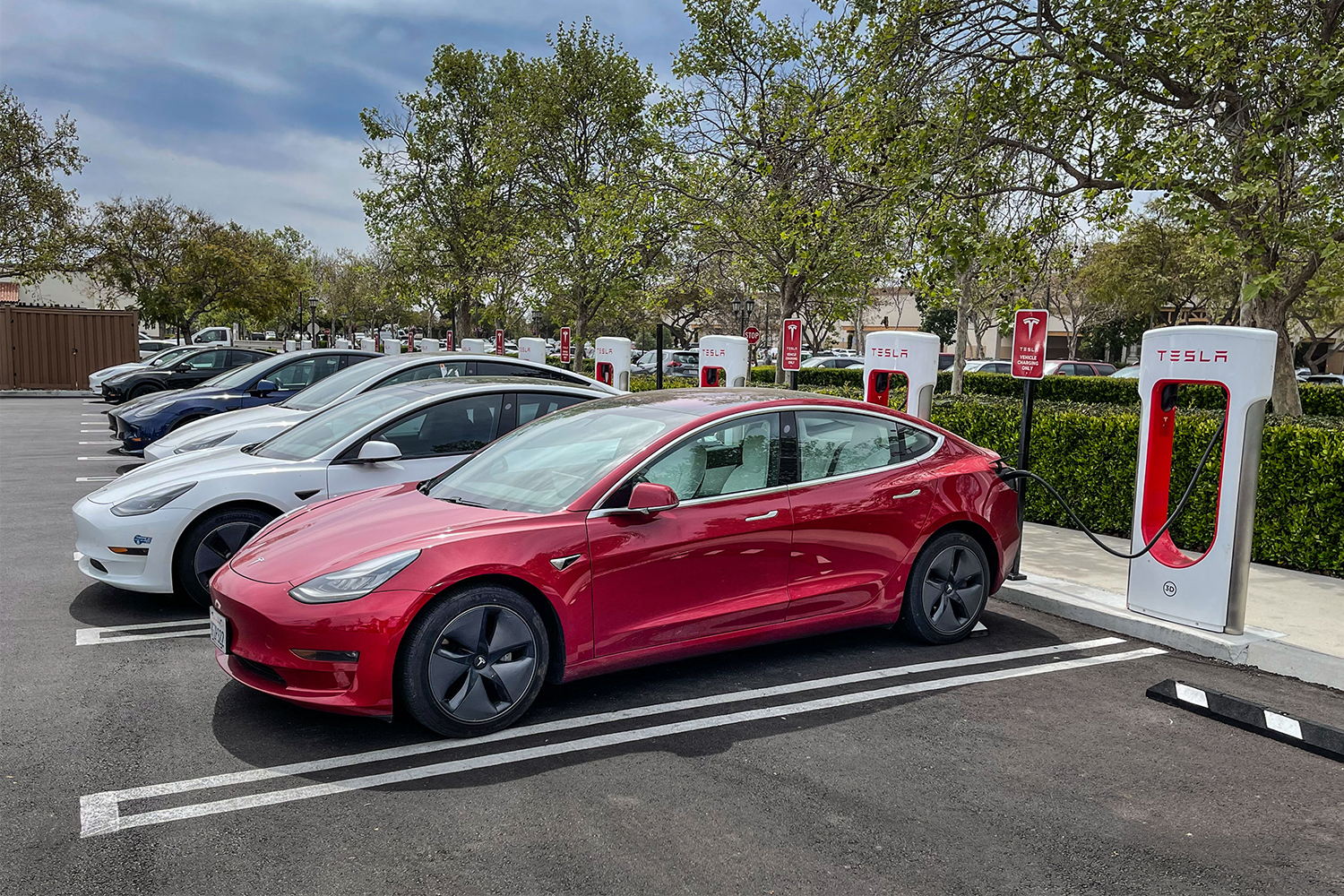 A row of Tesla electric vehicles filling their batteries at charging stations