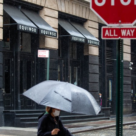 A woman walks past an Equinox in the rain.