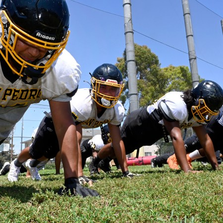 Members of a high school football team doing push-ups.