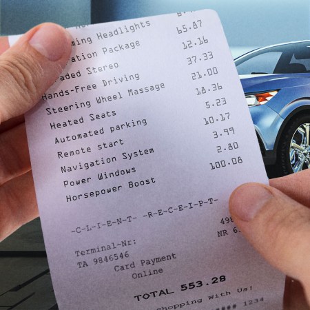 Hands holding a receipt for car feature subscriptions. Automakers are beginning to charge recurring subscription fees for certain features.