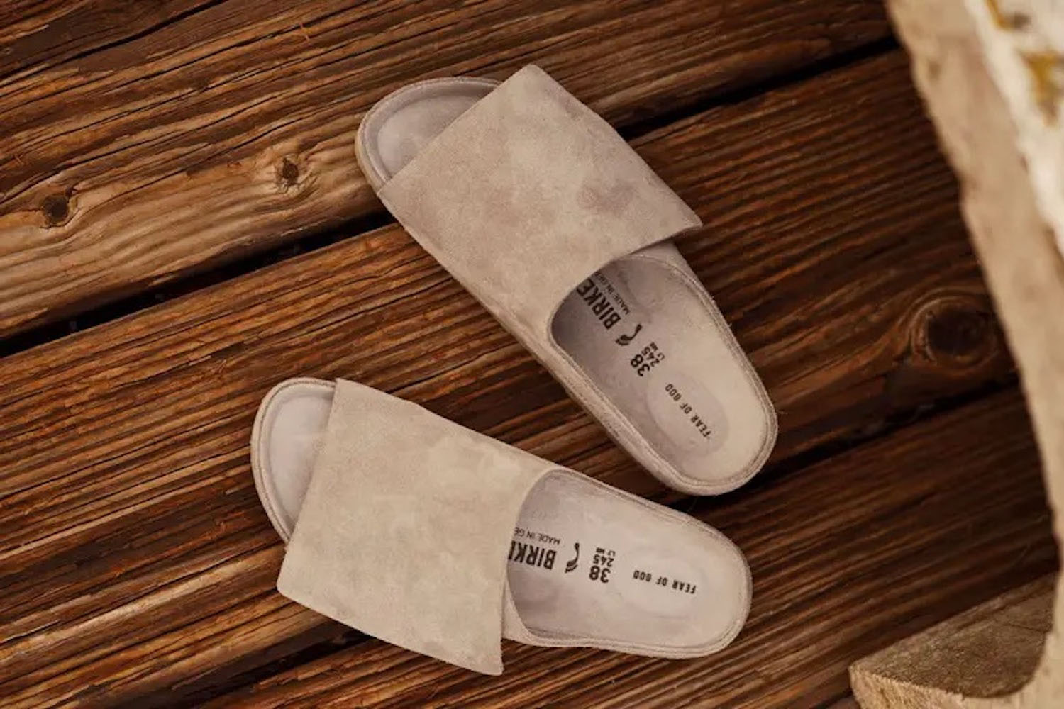 a pair of Fear of God x Birkenstock sandals on hardwood