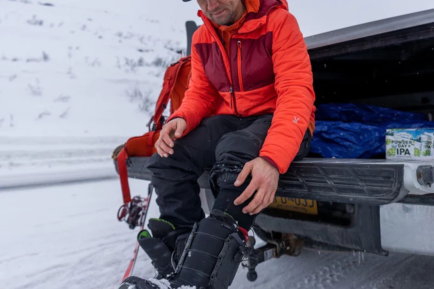 a model wearing an Ibex puffer hoodie in snowy conditions