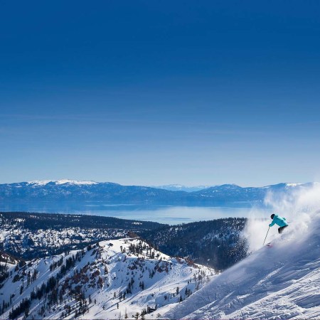 person downhill skiing against a blue sky in Palisades Tahoe