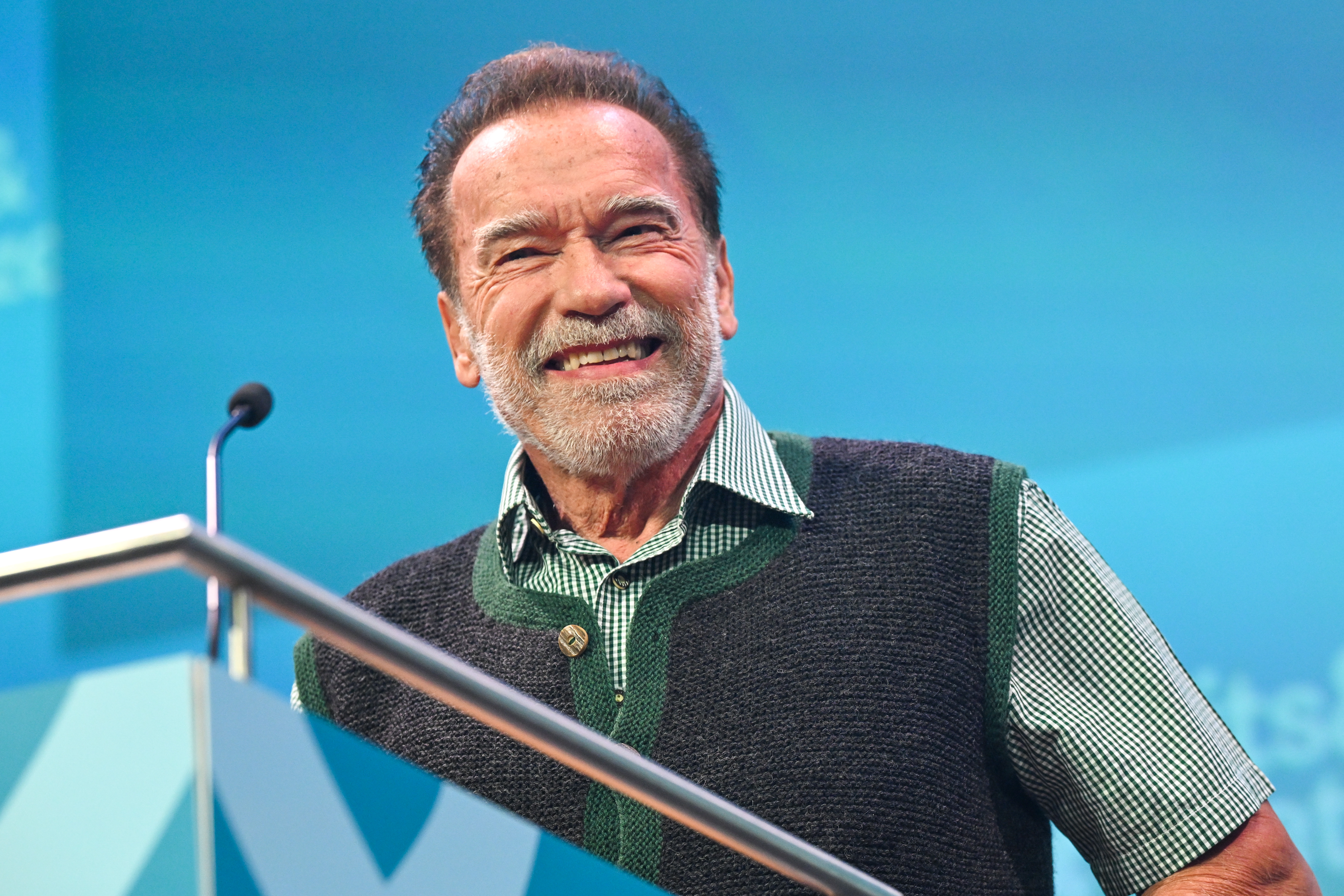 Arnold Schwarzenegger grinning at a podium.