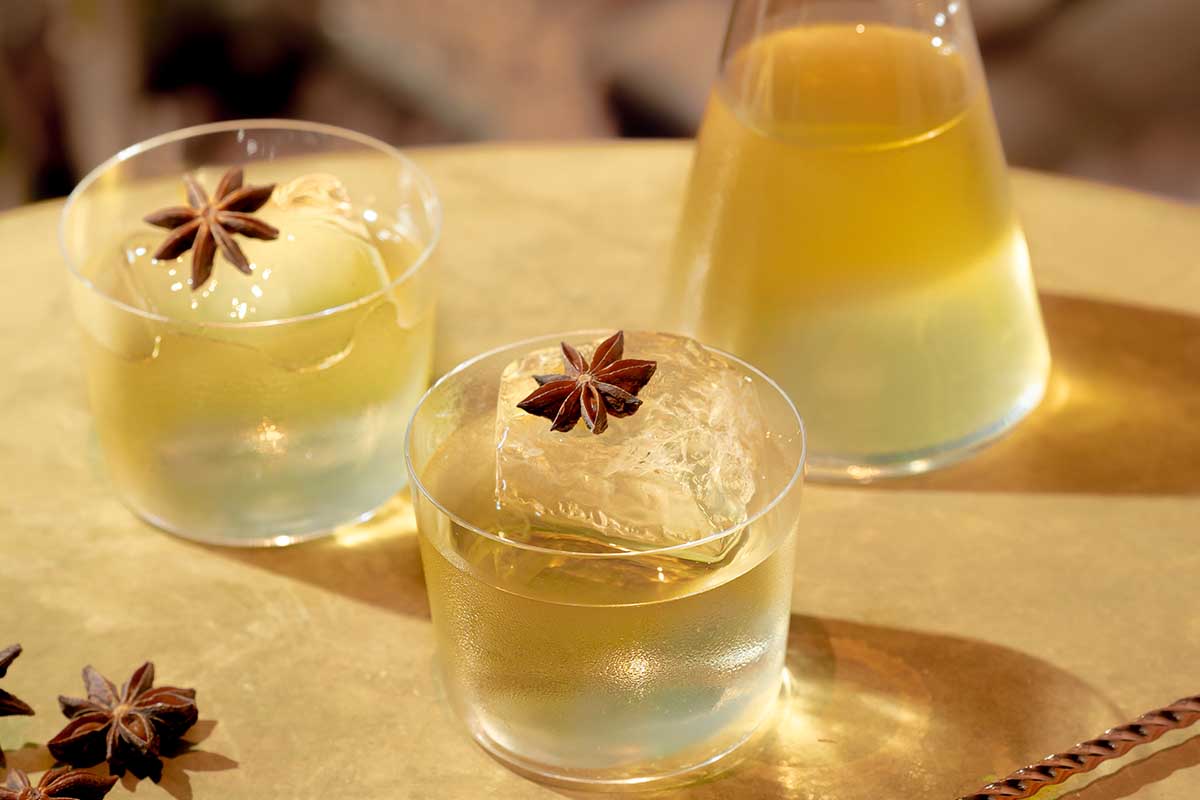 Two glasses and a decanter of a clarified milk punch made with Equiano Rum