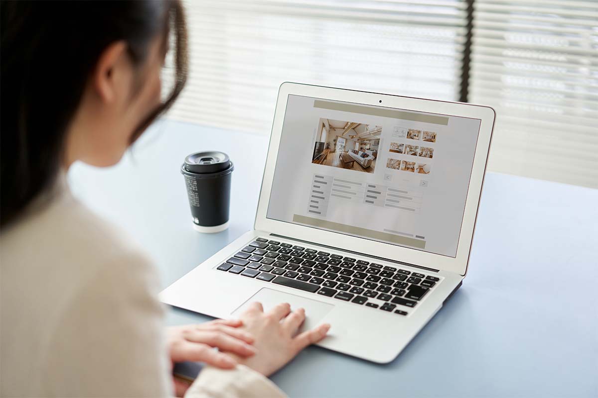 A woman at a desk looking at a real estate listing. Listings and other real estate work might be done now by ChatGPT, an AI-assisted chatbot.